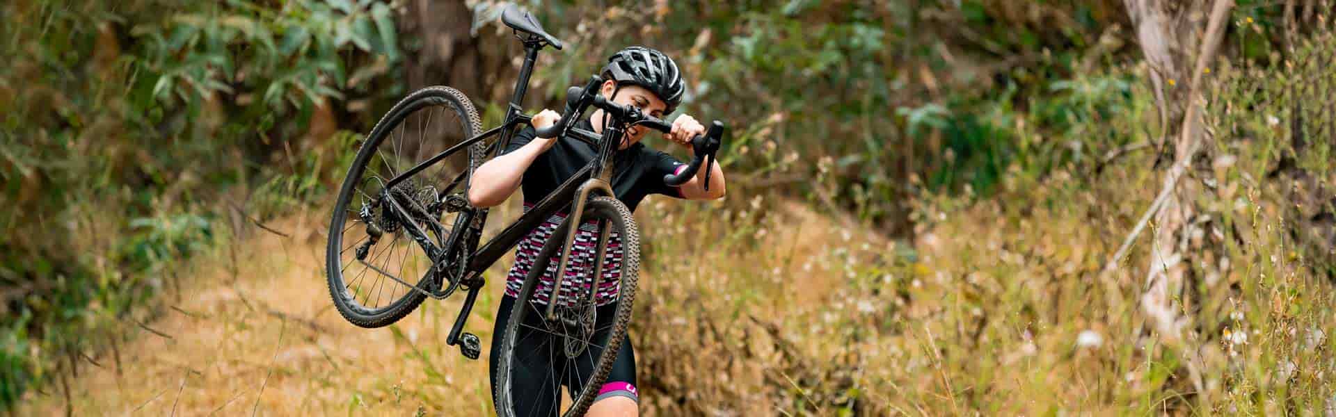 cyclist going through the woods with her bike